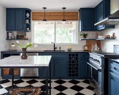 a black and white checkered floor in a kitchen with blue cabinets, an island countertop and two windows