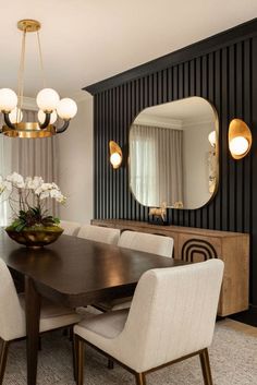 a dining room table with white chairs and a large mirror on the wall above it