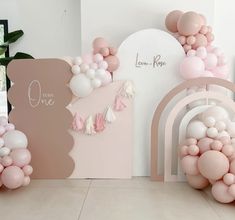 some balloons are hanging on the wall in front of a pink and white arch with tassels