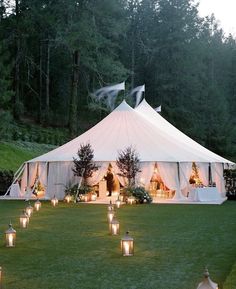 a large white tent with candles in the grass