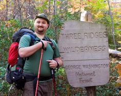 a man standing in front of a sign for three bridges wilderness, with hiking gear on