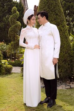 a man and woman dressed in white standing next to each other on the grass field