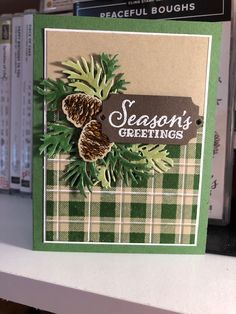 a close up of a card on a shelf with books in the background and pine cones