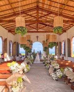 the inside of a church with flowers and greenery hanging from the ceiling, along with two rows of wooden pews