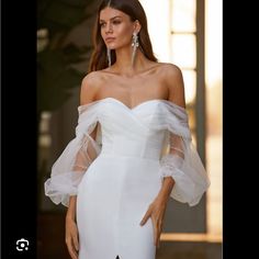 a woman wearing a white dress with sheer sleeves and an off the shoulder neckline