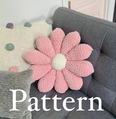 a gray couch with two pillows and a pink flower on the pillow that says pattern