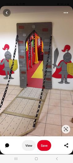 an indoor play area for children with castle doors and chains hanging from the ceiling, in front of a wall painted with cartoon characters