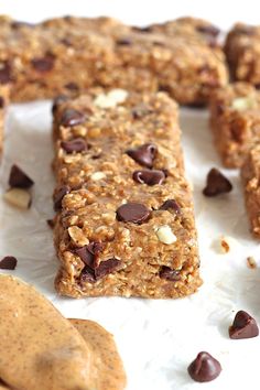 chocolate chip granola bars with peanut butter and oats scattered around them on a white surface