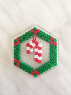 a christmas ornament made out of legos on a white surface with red and green beads