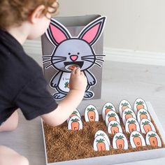 a little boy that is sitting in front of a box with carrots on it