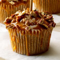 three cupcakes with nuts and caramel drizzled on the top