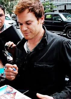 a man looking at his cell phone while standing next to a woman on the street