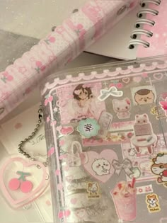 an open notebook with stickers on it and a pink case next to the book