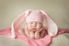 a newborn baby wearing a pink crochet bunny hat