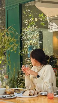 a woman sitting at a table in front of a window with food on the plate