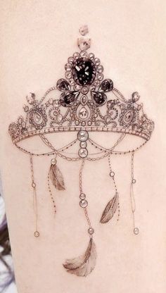 a woman's thigh with a tattoo on it that has feathers and beads hanging from it