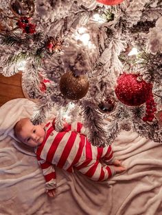 a baby laying in front of a christmas tree