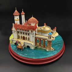 a miniature model of a castle on top of a blue body of water with red roof tops