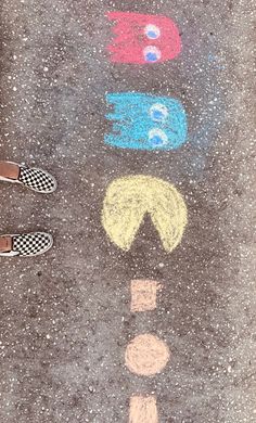 two people standing on the sidewalk with their feet in front of chalk drawings that look like faces