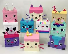 several colorful boxes with cats on them and one is made out of construction paper, the other has eyes