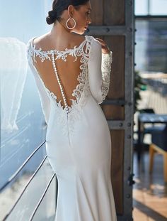 the back of a woman's wedding dress with long sleeves and an open back