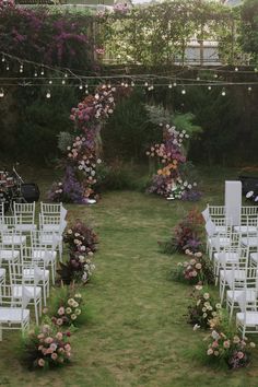 an outdoor ceremony set up with white chairs and flowers