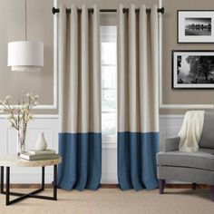 a living room filled with furniture and a window covered in blue and white curtains next to a gray chair