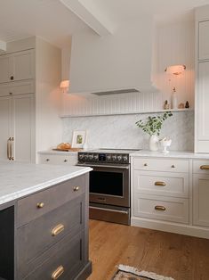 a kitchen with white cabinets and marble counter tops