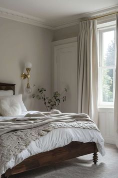 a bed with white sheets and pillows in a bedroom next to a window filled with curtains