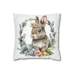 a white pillow with an image of a rabbit in the middle of it, surrounded by flowers