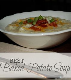 a white bowl filled with baked potato soup on top of a table next to a fork