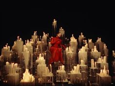 a woman standing in front of a large display of white candles with red clothing on