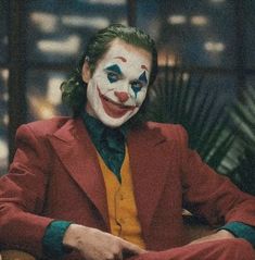 a man dressed as the joker sitting in a chair