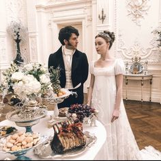 a man and woman standing in front of a table filled with food