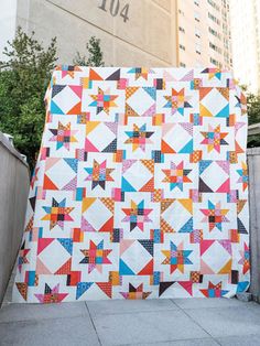 a colorful quilt on the ground in front of a tall building