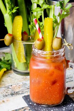 a jar filled with pickles and carrots on top of a table next to other vegetables