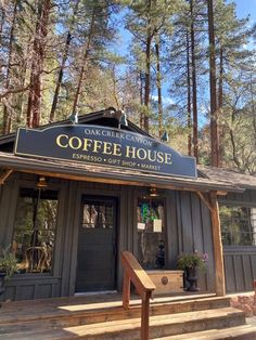 the coffee house is located in front of some tall trees and has stairs leading up to it