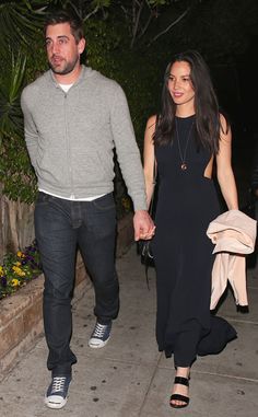 a man and woman holding hands while walking down the street