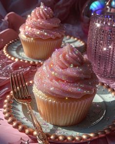 two cupcakes with pink frosting and sparkle on them sitting on a plate