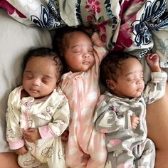 three baby babies laying next to each other on a bed