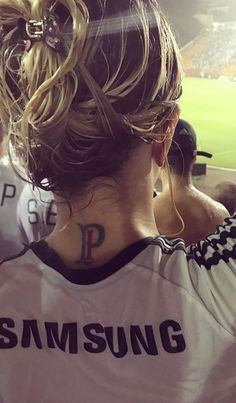 the back of a woman's head with tattoos on her left shoulder and right arm