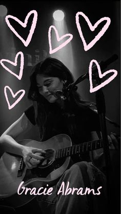 a girl playing guitar with hearts drawn on her face and the words love is in the air