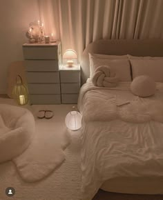 a bed with white sheets and pillows in a bedroom next to a night stand filled with candles