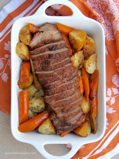 a white plate topped with meat and veggies on top of an orange table cloth