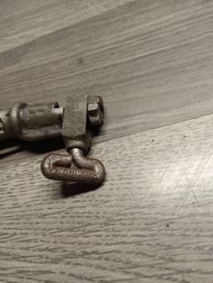 a close up of a metal hook on a wooden floor with a chain attached to it