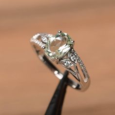 It is a natural green amethyst ring. The main stone is 6 mm*8 mm oval cut.weight about 1.14 carats.The basic metal is sterling silver and plated with rhodium.To change the metal to a solid gold (white/rose) or platinum is also available, please ask for a quotation if you want.You can also go to my shop Home for more elegant rings: https://www.etsy.com/shop/godjewelry?ref=hdr_shop_menu More green amethyst rings:https://www.etsy.com/shop/godjewelry?ref=seller-platform-mcnav&search_query=green+ Oval Green Amethyst Jewelry, Fine Jewelry Green Amethyst Oval Ring, Silver Green Amethyst Ring In Fine Jewelry Style, Silver Fine Jewelry Amethyst Ring, Elegant Green Oval Amethyst Ring, Elegant Silver Green Amethyst Ring, Oval Green Amethyst Ring With Accent Stones, Oval Green Amethyst Ring For Anniversary, Swiss Blue Topaz Ring