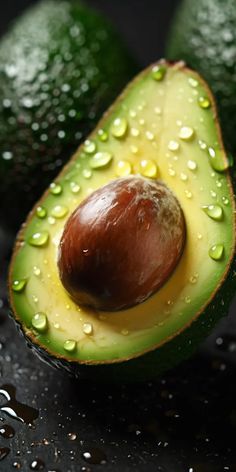 an avocado that has been cut in half with water droplets on the surface