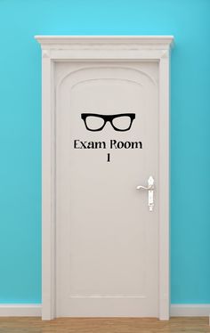 a door with the words exam room and glasses on it in front of a blue wall