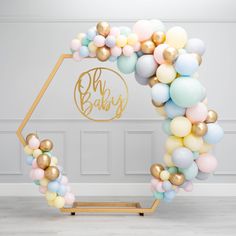 the balloon arch is decorated with pastel colors and gold foil balloons for a baby shower