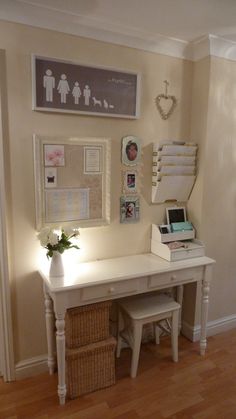 a white desk with flowers and pictures on the wall next to an entryway door